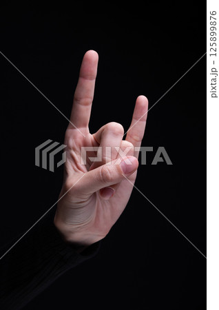 Goat gestures with female hand. Cool rocker gesture, youth style. Black background 125899876