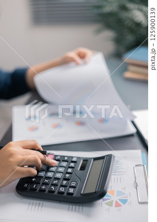 Finance bank tax expense accounting budget money businessman hand use calculator Financial calculate accountant close up calculator with graph chart write office desk Business expense analysis saving 125900139