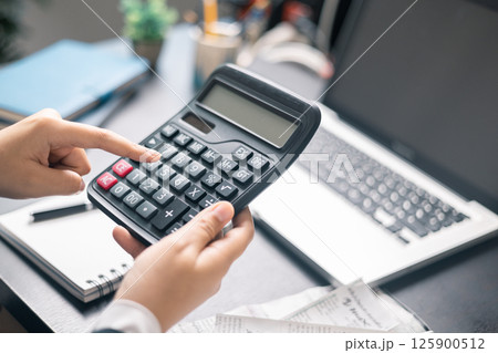 Finance bank tax expense accounting budget money businessman hand use calculator Financial calculate accountant close up calculator with graph chart write office desk Business expense analysis saving 125900512