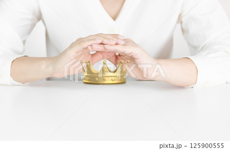 Protective Hands Shielding Golden Crown Representing Leadership and Success 125900555