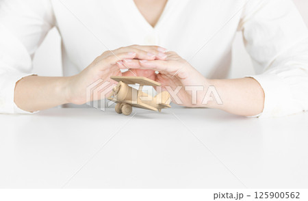 Hands Protecting Wooden Toy Airplane Representing Travel Dreams Hands Protecting Wooden Toy Airplane Representing Travel Dreams 125900562