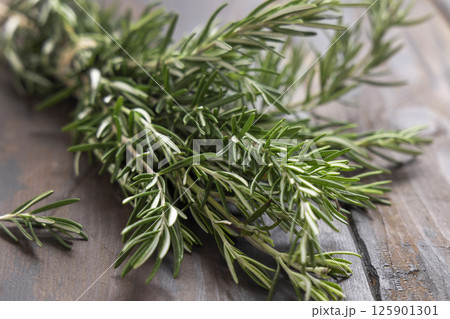 Fresh green rosemary sprigs on dark weathered wooden table closeup. Aromatic herb for culinary Fresh green rosemary sprigs on dark weathered wooden table closeup. Aromatic herb for culinary 125901301