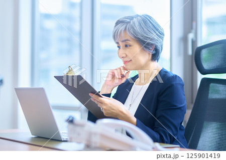 オフィスでデスクワークするシニア ビジネスウーマン オフィスでデスクワークするシニア ビジネスウーマン 125901419