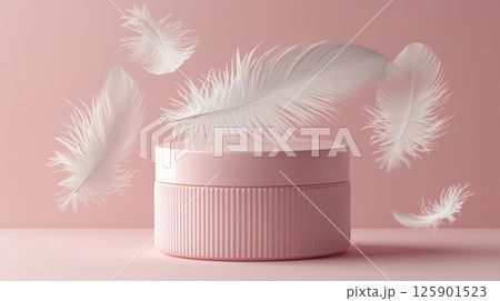 A soft pink product container sits on a pink background, surrounded by floating white feathers.  125901523