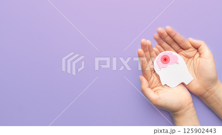 Hands holding human head with brain as pain red circle on purple background. Concept of headache, stroke disease, migraine, epilepsy, meningitis, brain tumor and dementia. Mental health. Hands holding human head with brain as pain red circle on purple background. Concept of headache, stroke disease, migraine, epilepsy, meningitis, brain tumor and dementia. Mental health. 125902443