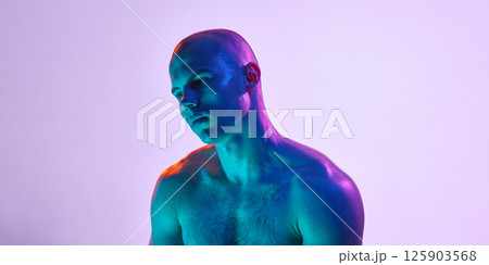 Portrait of young handsome bald man, posing shirtless with pensive expression on light purple background in neon light. 125903568