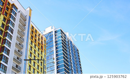 A cluster of tall buildings stands prominently against a clear blue sky 125903762