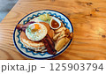 ベーコンと目玉焼きがのっているパンケーキ 125903794
