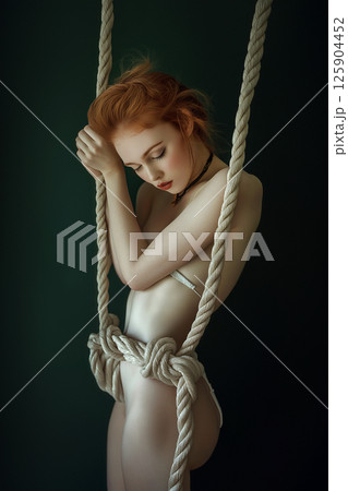 Beautiful woman tied with ropes, Japanese art of shibari, BDSM. Woman with ropes in a creative intimate setting, love game. Sexual games concept, aesthetic bandage. 125904452