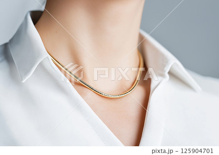 A close-up image of a woman wearing a simple yet elegant necklace, highlighting sophistication and minimalist jewelry design often seen in fashion and luxury accessories. 125904701