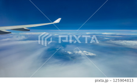 The view from the airplane window to the clouds. Airplane wing above thick blue and white clouds. Wonderful sky 125904813