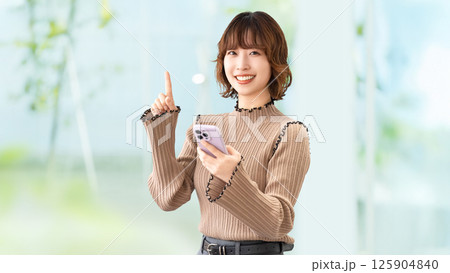 スマートフォンを持って案内をする笑顔の女性・ビジネスウーマン 125904840