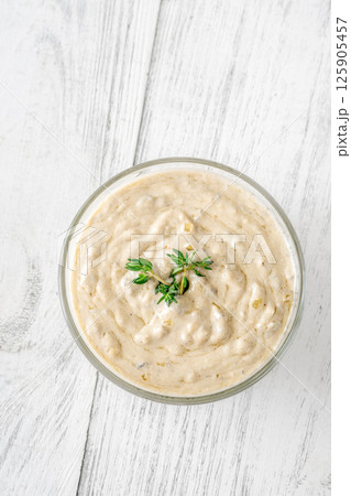 Creamy blue cheese sauce garnished with thyme in clear bowl on table 125905457