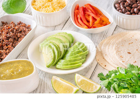 Fresh taco ingredients arranged with avocado, beef, salsa verde, and lime 125905485