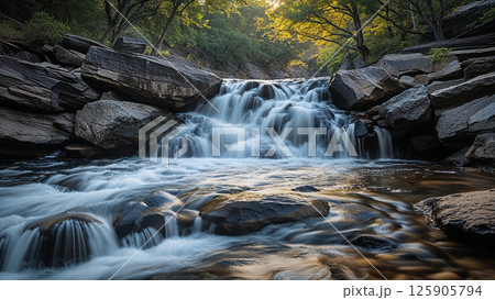 Waterfall cascading over rocks in a peaceful forest at sunset 125905794
