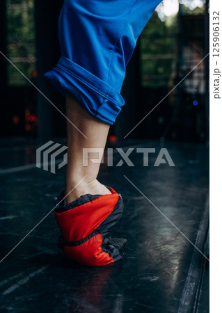 Ballet Dancer Practicing in Warm-up Booties on Stage Ballet Dancer Practicing in Warm-up Booties on Stage 125906132