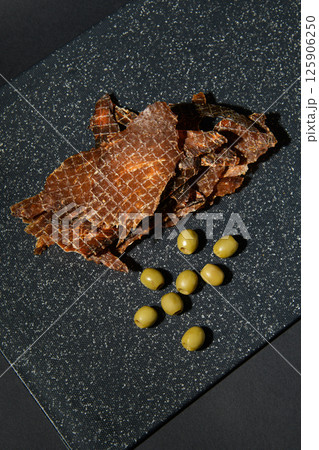 Jerky on the table with olives. View from above. Snack. 125906250