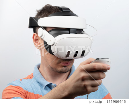 Man experiences virtual reality in bright indoor setting while holding controller Man experiences virtual reality in bright indoor setting while holding controller 125906446