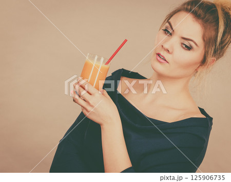 Thinking woman holding fresh orange juice Thinking woman holding fresh orange juice 125906735