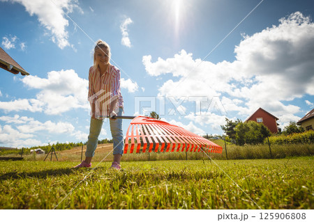 Unusual angle of woman raking leaves 125906808