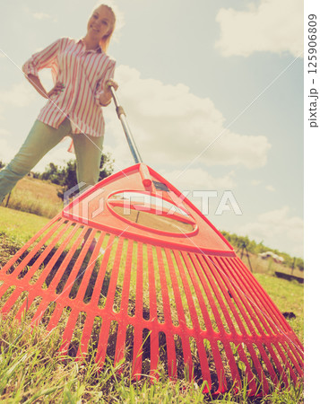 Unusual angle of woman raking leaves 125906809
