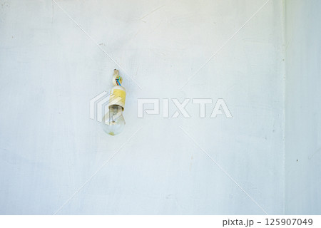 Light bulb with power cables sticking out of concrete wall. Light bulb with power cables sticking out of concrete wall. 125907049