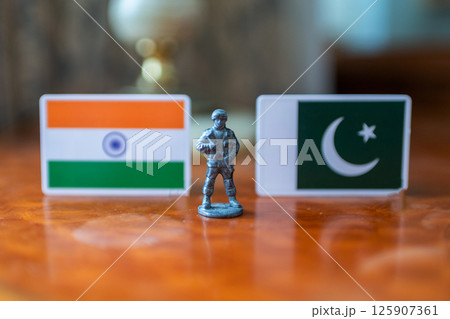 A tin soldier on the background of the flags of India and Pakistan. India Pakistan military conflict 125907361