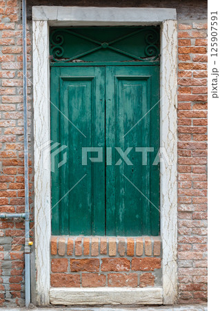 Old Green Wooden Door in Brick Wall 125907591