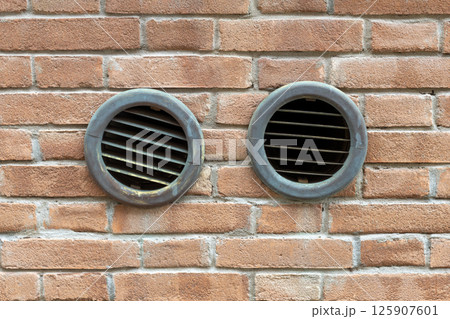 Two Round Vent Grilles in Brick Wall Two Round Vent Grilles in Brick Wall 125907601