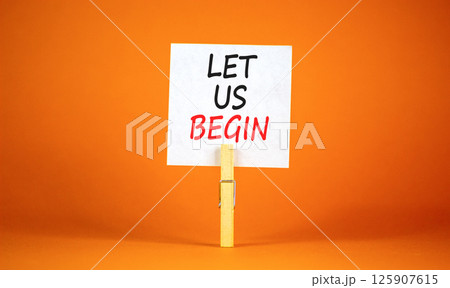 Let us begin symbol. Concept words Let us begin on beautiful white paper on clothespin. Beautiful orange background. Business motivational let us begin concept. Copy space. 125907615