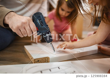 Father and children building a wooden project together at home 125908164
