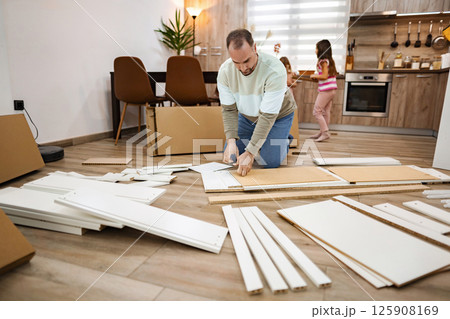 Father assembling furniture in a cozy family living room together Father assembling furniture in a cozy family living room together 125908169