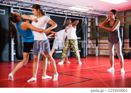 Two woman is training on self defense course in gym Two woman is training on self defense course in gym 125910001