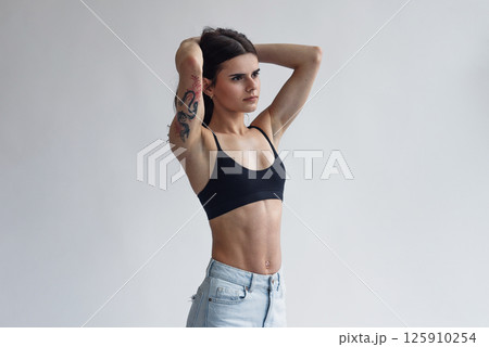 Charming skinny beautiful girl with perfect abs in jeans and black top isolated on light background Charming skinny beautiful girl with perfect abs in jeans and black top isolated on light background 125910254