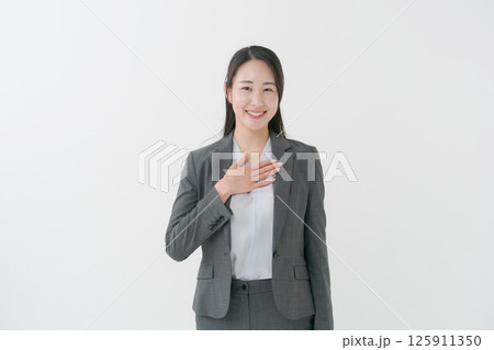 胸に手を当てるスーツ姿の女性 125911350