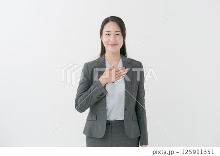 胸に手を当てるスーツ姿の女性 125911351