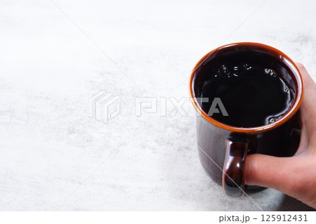お気に入りのマグカップに淹れたてのコーヒーを入れてひと休みしているイメージ 125912431