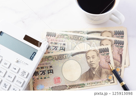 福沢諭吉の肖像の一万円紙幣と電卓、淹れたてのコーヒー 福沢諭吉の肖像の一万円紙幣と電卓、淹れたてのコーヒー 125913098