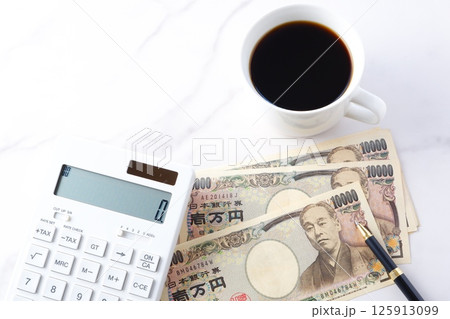 福沢諭吉の肖像の一万円紙幣と電卓、淹れたてのコーヒー 125913099