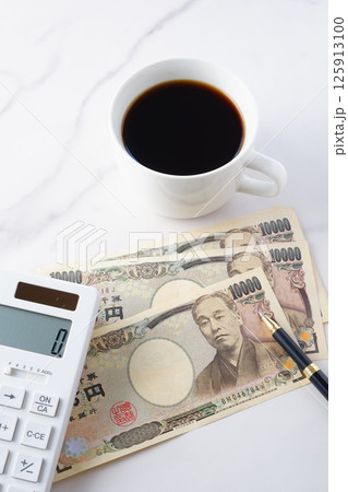 福沢諭吉の肖像の一万円紙幣と電卓、淹れたてのコーヒー 125913100