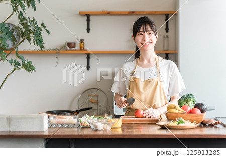 キッチンで料理をする若いアジア人女性（切る・包丁・クッキング・手料理） 125913285