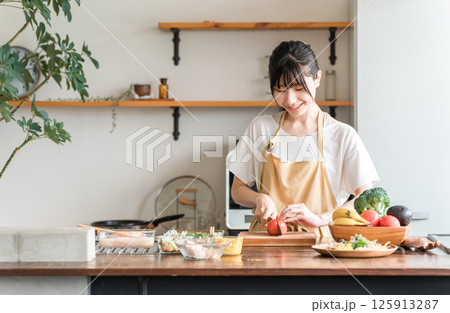 キッチンで料理をする若いアジア人女性（切る・包丁・クッキング・手料理） 125913287