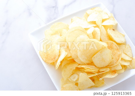 白い皿に山盛りのポテトチップス 白い皿に山盛りのポテトチップス 125913365