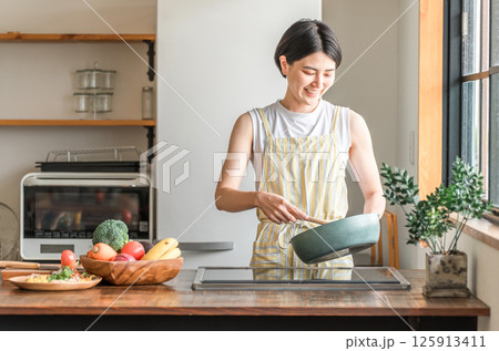 キッチンで料理をする若いアジア人女性（クッキング・手料理,炒める） 125913411