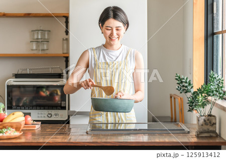 キッチンで料理をする若いアジア人女性（クッキング・手料理,炒める） 125913412