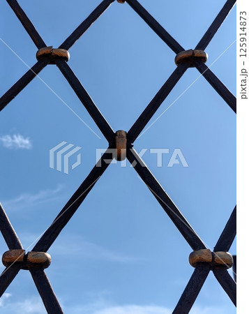 metal stylish sturdy lattice against bright blue sky with wispy clouds in afternoon. closeup. metal stylish sturdy lattice against bright blue sky with wispy clouds in afternoon. closeup. 125914873