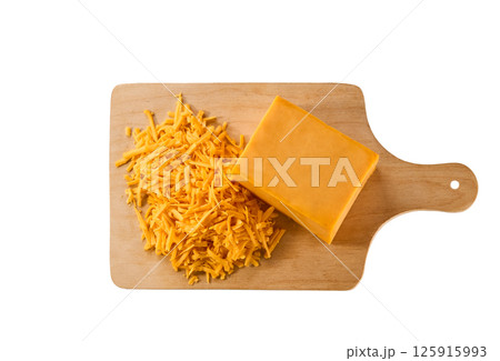 grated cheddar cheese on a cutting board isolated on a white background, top view. grated cheddar cheese on a cutting board isolated on a white background, top view. 125915993