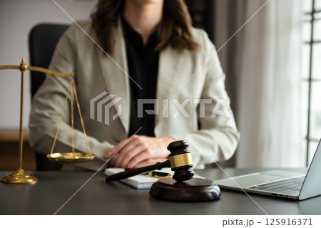 justice and law concept.law theme wooden desk, books, balance. Male judge in a courtroom the gavel,working with digital tablet computer on table justice and law concept.law theme wooden desk, books, balance. Male judge in a courtroom the gavel,working with digital tablet computer on table 125916371