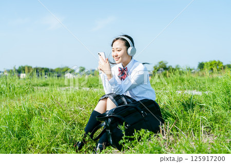 ヘッドフォンで音楽を聴く女子高校生 125917200