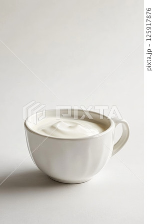 Calm white ceramic cup holding creamy natural yogurt on a plain background 125917876